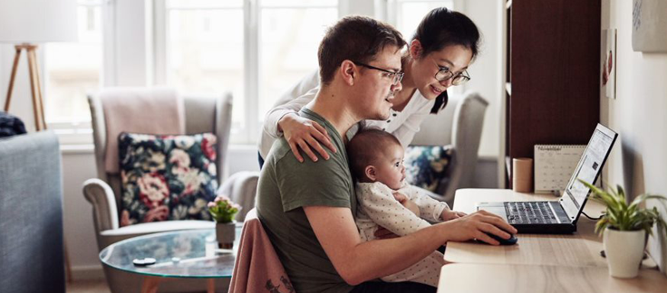 parents and baby looking at laptop
